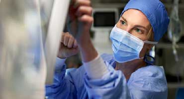 A doctor in surgical gear in an operating room checking a monitor