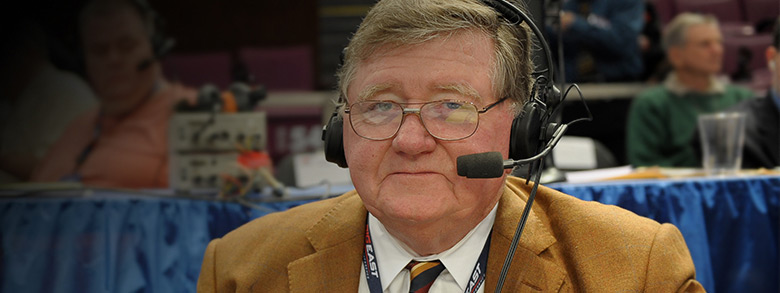Sportscaster Bill Hillgrove with microphone and headphones on during a broadcast