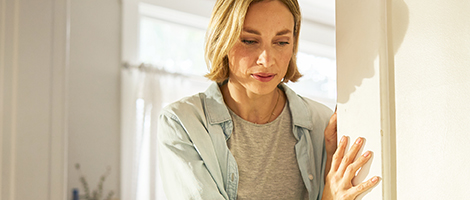 A woman in her house holding herself upright on a door frame