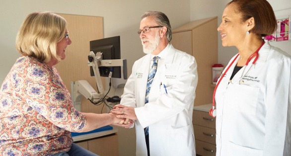 two ahn oncology doctors greeting a female patient in an exam room