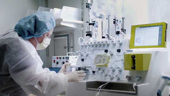 Cancer researcher in protective lab gear working with equipment in laboratory
