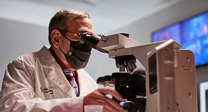  AHN researcher looking at samples through a microscope
