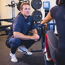 A trainer helping a patient with weight training.