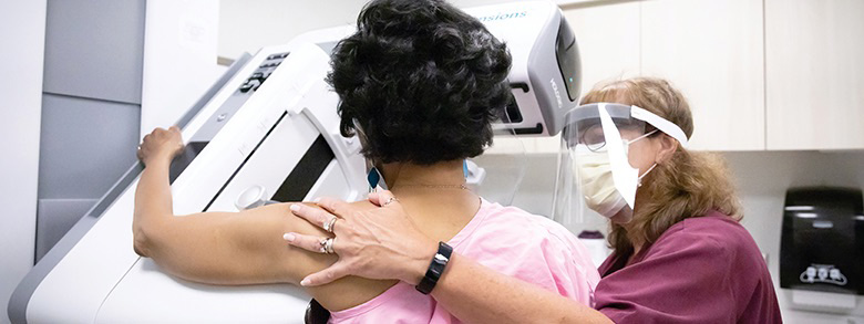 A woman being helped by a medical professional getting her breast scanned.