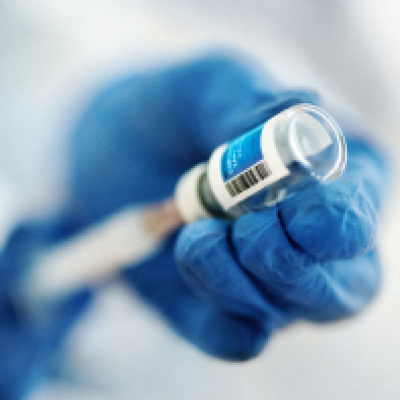 gloved hands using a syringe to withdraw medicine from a vial