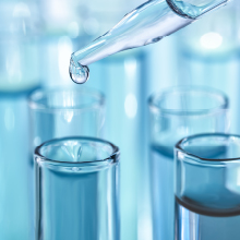 A clear pipette drops liquid into a test tube.
