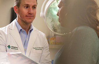 Dermatologist reviewing records and consulting with a patient about treatment options in a clinic setting