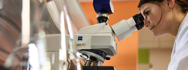 Researcher at AHN conducting skin cancer research using a microscope.