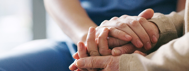 Two pairs of hands clasped together in a gesture of support and compassion.
