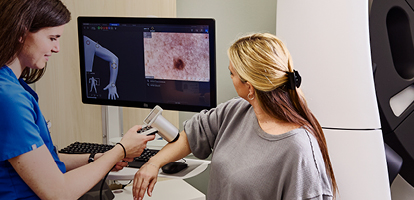 A medical professional using mole mapping technology to examine a patient's skin for melanoma at AHN.