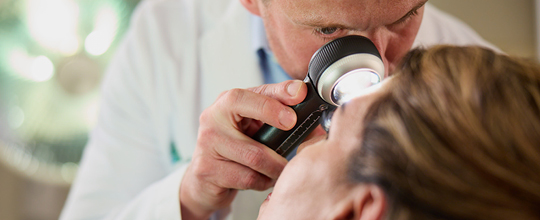 Dermatologist examining a patient's skin with a magnifying light