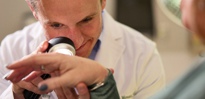 Dermatologist examining a patient's skin with a magnifying light to check for Merkel cell carcinoma