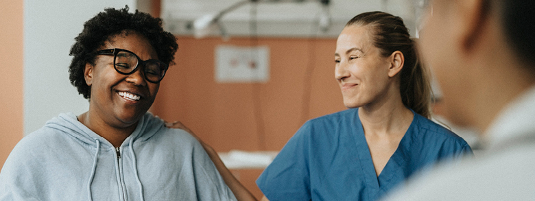 Smiling patient standing next to two medical professionals.