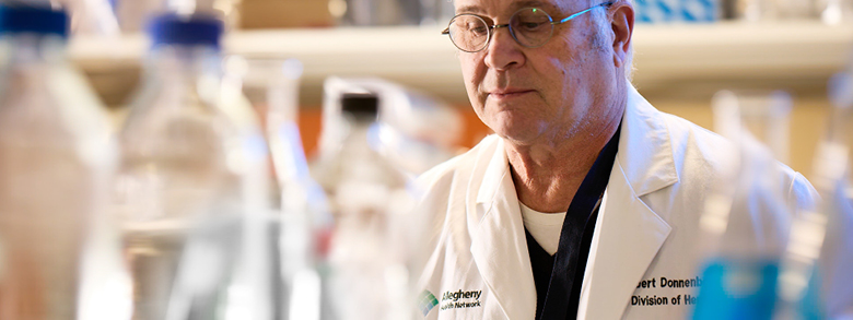 Researcher analyzes skin cancer cells in lab, contributing to clinical trial advancements at AHN.