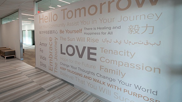 A white wall in the Breast Cancer Center of Excellence covered in gold text with phrases like "Hello Tomorrow", "Be Yourself", and "Love". 