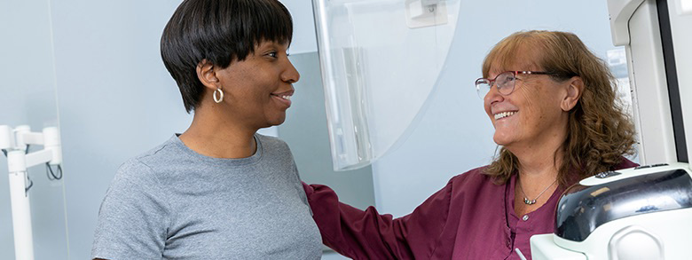 A health care professional putting her hand on a patient's shoulder and smiles.