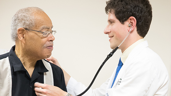 A doctor using a stethoscope on a smiling patient 