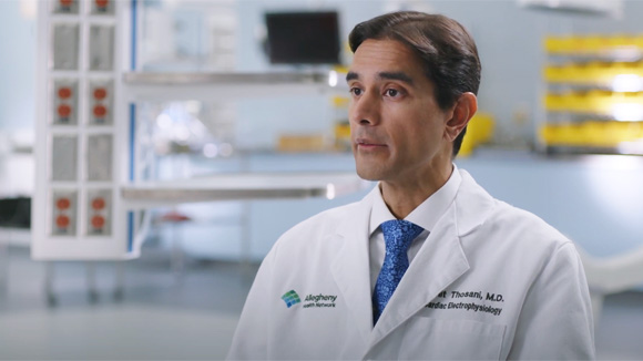 Dr. Amit Thosani, the Director of cardiac electrophysiology at AHN Cardiovascular Institute, sitting on a chair in a surgery suite.