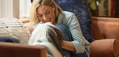 A woman petting her dog on her couch