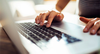 Hands typing on a laptop keyboard