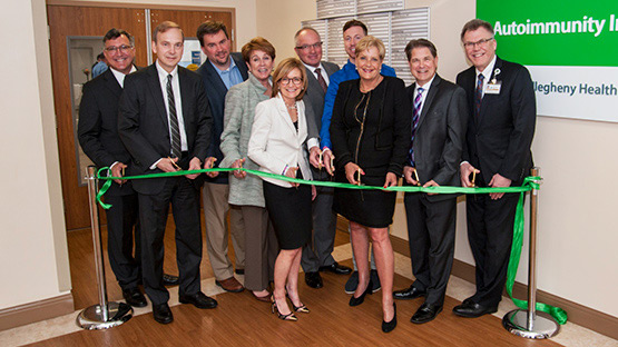 A group shot of AHN leadership and physicians inside one of the updated autoimmune facilities cutting the ribbon to mark it as open.