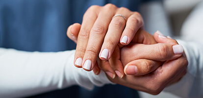 Close-up of two hands clasped together, one with a ring