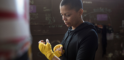 A woman wrapping her hands in front of punching bag.