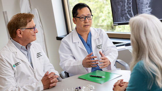 Two AHN Neuroscience doctors discussing treatment opinions with a patient.