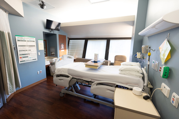 A comfy hospital room with a bed and a table ready for someone who needs epilepsy monitoring.