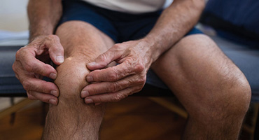 image of a man holding his knee in a doctor's office