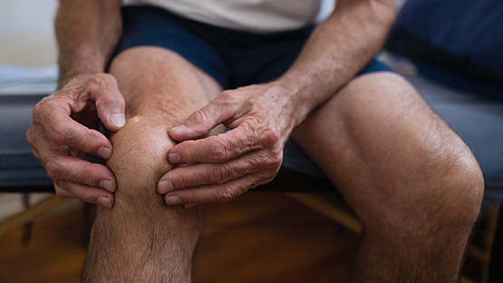 image of a man holding his knee in a doctor's office