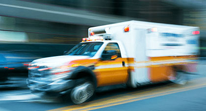 Emergency medical services staff driving an ambulance in traffic with its lights flashing.
