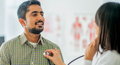 A physician using a stethoscope on a patient.