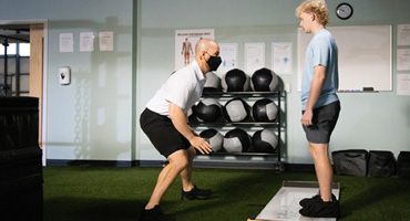 An AHN trainer running a student athlete through mobility drills.