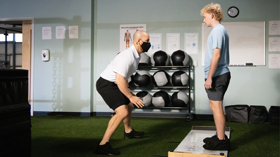 An AHN trainer running a student athlete through mobility drills.