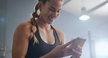 A woman in workout clothing looking at her phone.