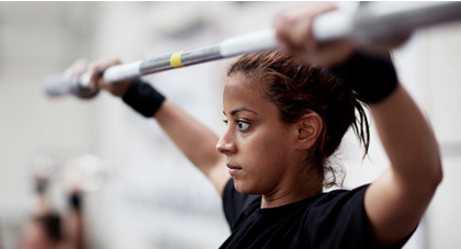 A young woman lifting a barbell above her head.