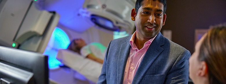 Dr. Fernando smiling while a cancer screening in taking place in the background