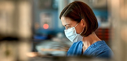 Female medical professional in a mask looking down