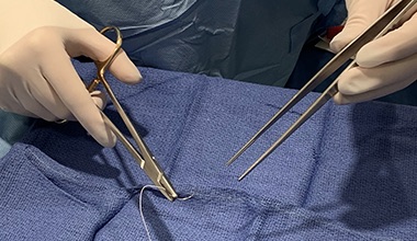 Medical professionals wearing protective equipment during surgery looking down in an operating room 