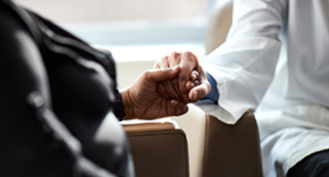 AHN doctor holding a patient's hand.