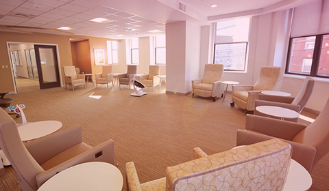 A Group Room at the Alexis Joy Center with comfortable chairs and tables in a U shape along the wall.