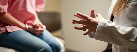 AHN patient sitting on a exam table while talking to a doctor.