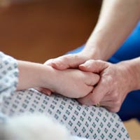 Close up view of a medical professional holding a patient's hand