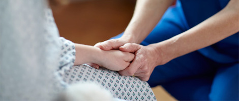 Close up view of a medical professional holding a patient's hand