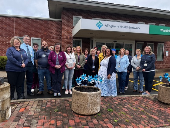 Officials from WMH and social service agencies stand in front of hospital with pinwheel display